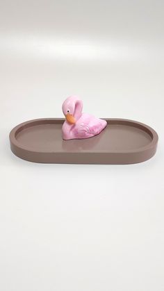 a pink duck sitting on top of a brown tray