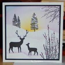 a card with two deer standing in the snow at night, and trees behind it