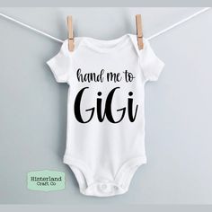 a baby bodysuit that says hand me to gigi on it hanging from a clothes line