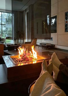 a person sitting in front of a fire pit with their feet up on the table