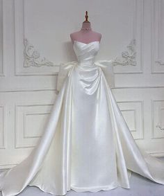 a white wedding dress on display in front of a wall