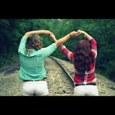 two people are holding hands while standing on the train tracks with their arms around each other