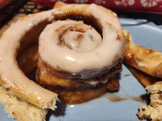 a cinnamon roll with icing sitting on top of a blue plate next to other pastries