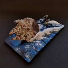 a paper model of a space ship floating on top of the ocean with waves and clouds