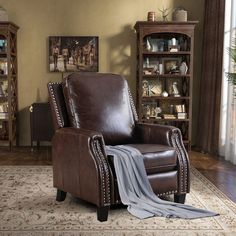 a brown leather recliner chair sitting on top of a rug in a living room