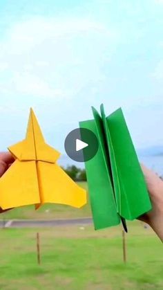 someone is holding two origami stars in their hands, one yellow and the other green