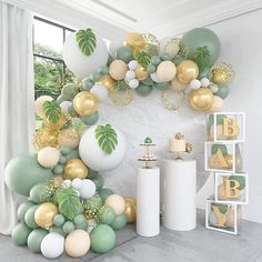 a room filled with balloons and greenery next to a wall mounted on the wall