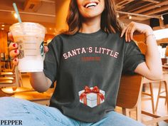 Keep the holiday fun going with this playful "Santa's Little Secret" maternity shirt! Styled in a classic collegiate font and featuring a cute wrapped present with a red bow over the baby bump, this tee is perfect for a festive pregnancy reveal or just showing off your holiday spirit. Whether you're sharing your exciting news or attending a holiday baby shower, this comfy shirt is a great way to celebrate your growing family in style. PROCESSING & SHIPPING Processing time is approx 1-7 business Collegiate Font, Holiday Baby Shower, Christmas Pregnancy Announcement, Christmas Pregnancy, Maternity Shirt, Maternity Tees, Pregnancy Reveal, Holiday Baby, Comfy Shirts