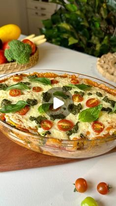 a pizza pie sitting on top of a wooden cutting board next to vegetables and fruit