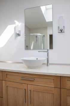 a bathroom sink sitting under a large mirror next to a wooden cabinet and counter top