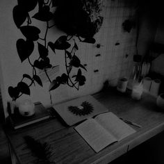 an open book sitting on top of a wooden table next to a candle and potted plant