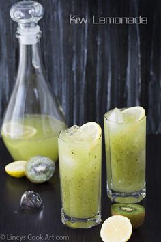 two glasses filled with green liquid next to sliced kiwis