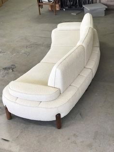 a white couch sitting on top of a floor next to a pile of furniture in a room