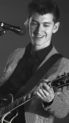 a young man is playing the guitar in front of a microphone