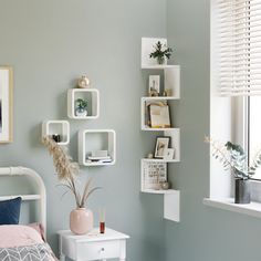 a bed room with a neatly made bed and shelves on the wall next to it