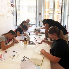 a group of people sitting at a table with notebooks and pens