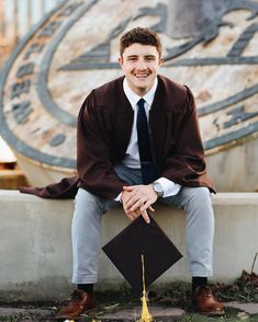 a man in a graduation cap and gown sitting on a bench