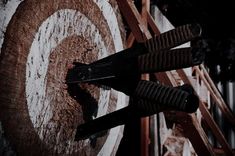 an arrow stuck in the center of a wooden target with rusted metal bars on it