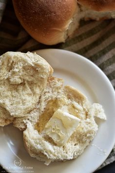 two rolls on a plate with butter spread on them next to the buns that have been cut in half