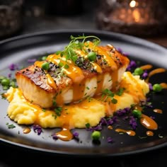 a black plate topped with food and garnished with green onions, peas and sauce