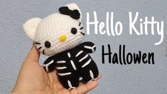 a hand holding a hello kitty doll with black and white knitted skeleton on it