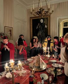 a group of people standing around a table with candles in front of them and plates on the table