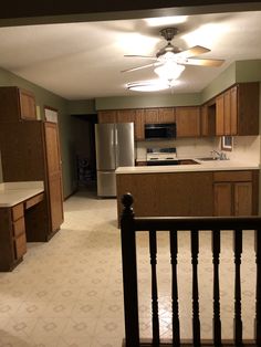 an empty kitchen with wooden cabinets and white tile flooring