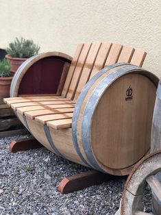 two wooden barrels sitting next to each other on top of gravel covered ground with potted plants in the background