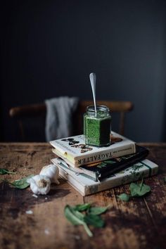 a stack of books sitting on top of each other with a jar filled with green liquid