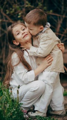 two children are hugging each other in the grass