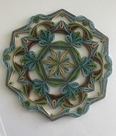 an intricately designed paper plate on a white surface with blue and green swirls