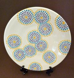 a white plate with blue and yellow dots on it sitting on a brown table top