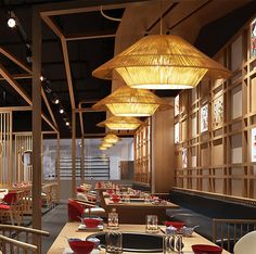 an empty restaurant with wooden tables and chairs, red plates on the table and yellow lights hanging from the ceiling