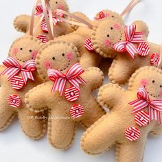 small brown teddy bears with red and white bows on their heads are hanging from twine strings