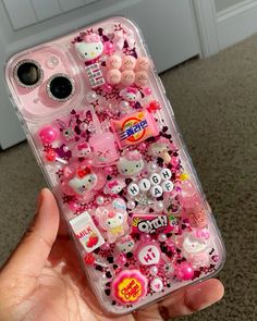 someone is holding their cell phone covered in hello kitty stickers and charms for the camera