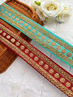 two pieces of red and gold ribbon sitting next to each other on top of a table