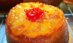 a pineapple upside down cake sitting on a cooling rack in a bakery display case