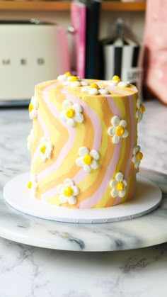 a yellow and pink cake sitting on top of a white plate covered in frosting