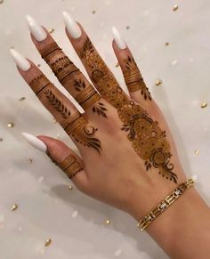 a woman's hand with henna tattoos and white nail polishes on it