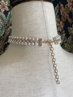 Our most luxurious adornment to date; this faux-pearl-beaded choker necklace has double rows of pearl beads adorned with glass crystal accents, a large encircled faux pearl cabochon, and gold colored adjustable hardware to fit your neck perfectly. Sizing: One Size Neck Circumference 12-16 Inches / 30-40 CentimetersAdjustable Claw Clasp Closure Glamorous Round Pearl Jewelry, Adjustable Pearl Embellished Choker Necklace, Elegant Metal Beaded Choker, Glamorous Pearl Jewelry With Pearl Chain, Party Pearl Chain Choker With Round Beads, Vintage Pearl Jewelry With Rhinestones, Vintage Pearl Beaded Choker, Costume Jewelry With Pearls And Rhinestones, Pearl Embellished Choker