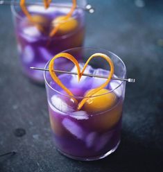 two glasses filled with purple liquid and orange peels