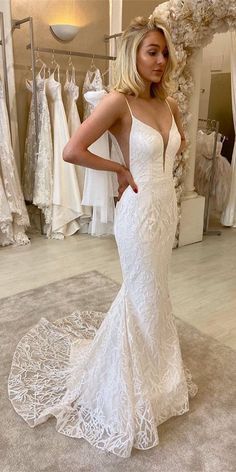 a woman standing in front of a mirror wearing a white dress and posing for the camera