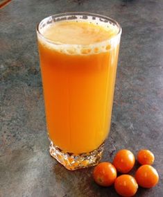 a glass filled with orange juice next to some fruit