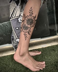 a woman's foot with a sunflower tattoo on the side of her leg