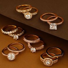 five different types of rings on a brown surface with one diamond ring in the middle