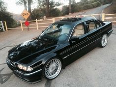 a black car parked in front of a wooden fence