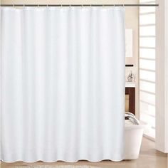 a white shower curtain in a bathroom next to a bathtub and rug on the floor