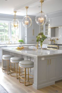 a large kitchen with marble counter tops and gold accents