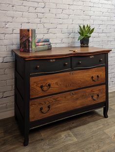 a wooden dresser with two drawers and a potted plant sitting on top of it