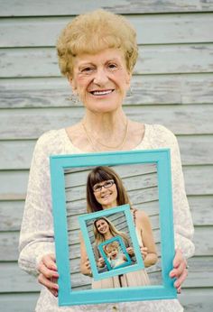 an older woman holding up a blue frame with a picture of her daughter on it